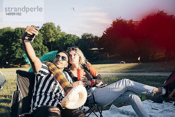 Freunde nehmen Selfie auf Smartphone  während sie bei einer Veranstaltung mit Ballon sitzen