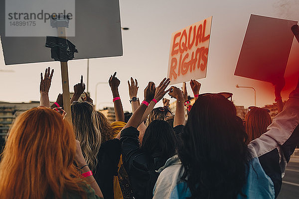 Rückansicht von jungen Frauen  die beim Marschieren in der Stadt für gleiche Rechte protestieren