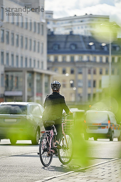 Erwachsene Pendlerinnen in voller Länge mit dem Fahrrad auf der Straße in der Stadt