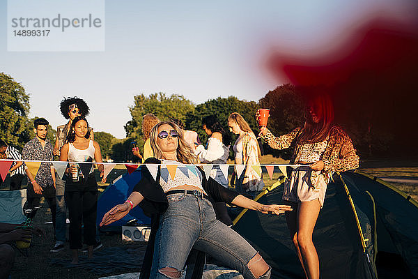 Junge Freunde führen Limbo-Tanz auf  während sie beim Musikfestival zelten