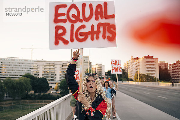 Frauen mit Plakatschreien beim Marschieren für Gleichberechtigung auf der Brücke in der Stadt