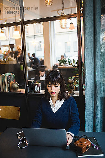 Selbstbewusste Geschäftsfrau mit Laptop am Schreibtisch im Kreativbüro