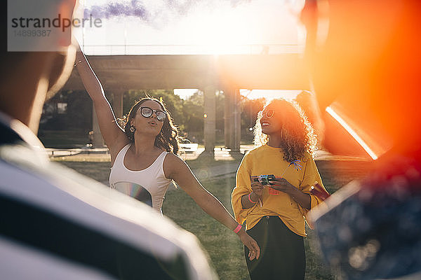 Verspielte Frau amüsiert sich mit Freunden während eines Musikfestivals an einem sonnigen Tag