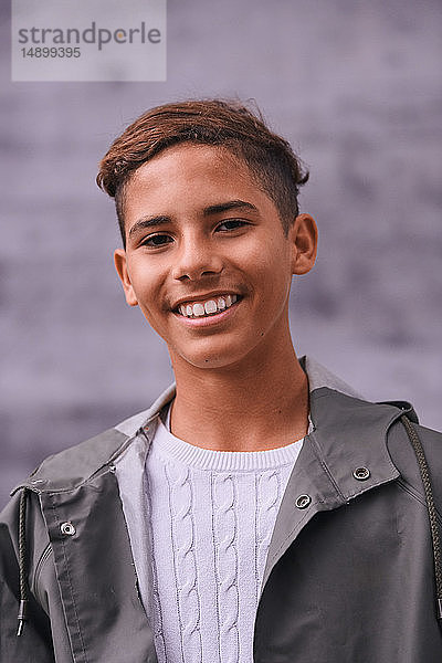 Porträt eines lächelnden Teenagers in Regenmantel auf dem Spielplatz