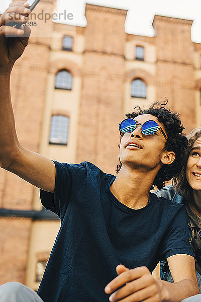 Modischer Teenager nimmt Selfie mit Freundin in die Stadt