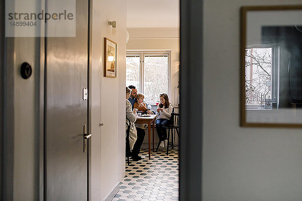Familie sitzt auf Stühlen in der Küche und sieht durch die Tür zu Hause