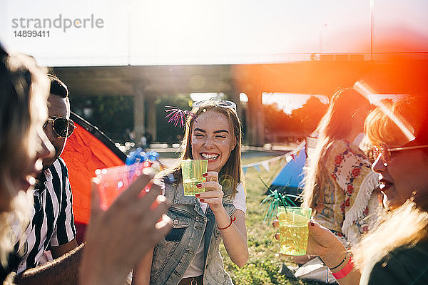 Lächelnde Freunde geniessen Getränke bei Musikkonzert im Sommer