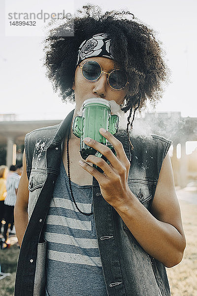 Junger Mann trinkt beim Musikfestival aus dem Glas