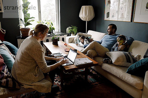 Familie nutzt verschiedene Technologien im Wohnzimmer zu Hause