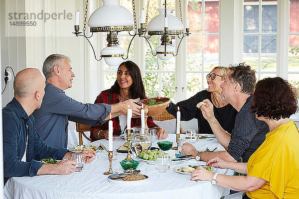 Glückliche reife Freunde  die während des geselligen Beisammenseins zu Hause im Speisesaal zusammen zu Mittag essen