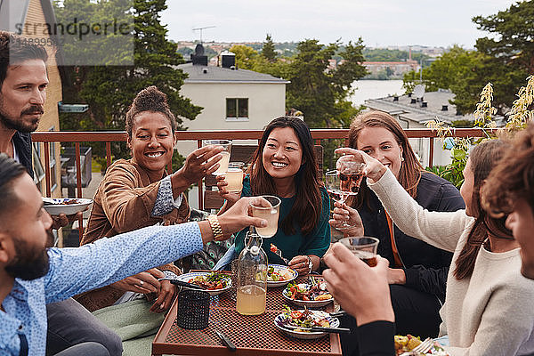 Glückliche Freunde stoßen auf der Terrasse auf Getränke an