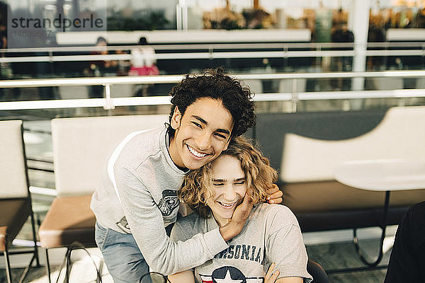 Porträt eines fröhlichen Teenagers  der einen Freund im Restaurant umarmt