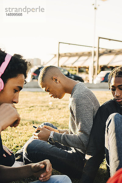 Männliche Freunde sitzen bei Sonnenschein auf dem Feld