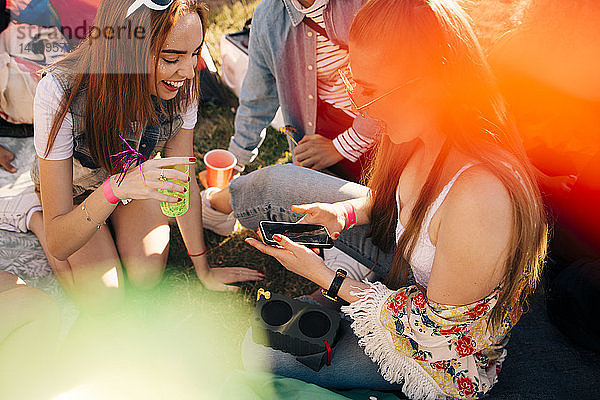 Hoher Blickwinkel auf Freunde  die während eines Musikfestivals über ein Mobiltelefon sprechen