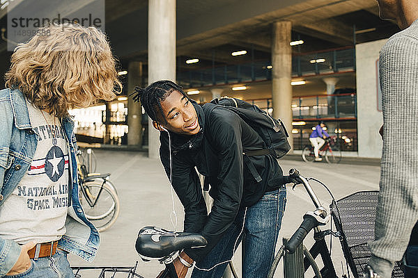 Teenager  der beim Bücken mit dem Fahrrad und Freunden auf der Straße der Stadt wegschaut