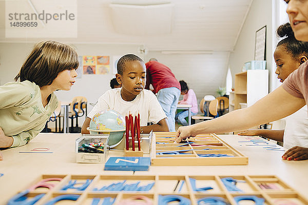 Schüler lernen Rechtschreibung am Tisch durch den Lehrer im Klassenzimmer