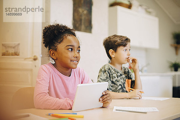 Junge lernt durch digitales Tablett  während er mit einem Freund im Klassenzimmer sitzt