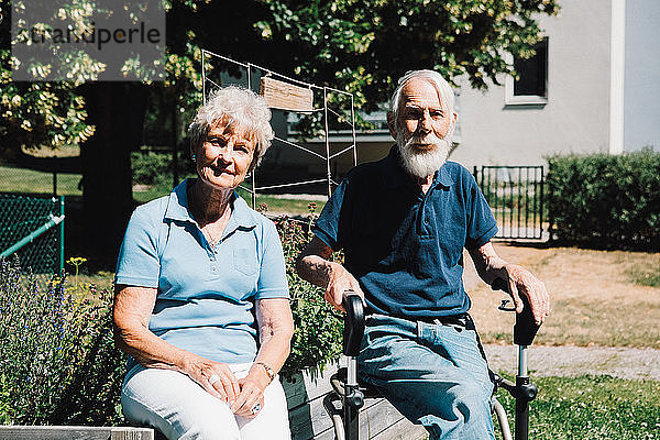 Porträt eines lächelnden älteren Mannes und einer lächelnden Frau im Ruhestand  die im Hinterhof sitzen