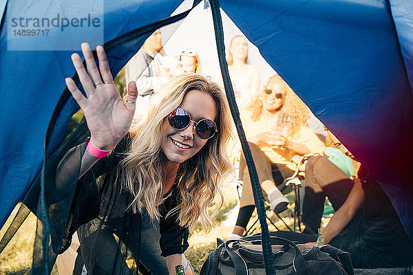 Porträt einer lächelnden Frau mit Freunden  die im Zelt auf das Festival schauen