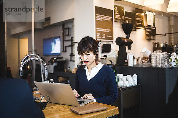 Selbstbewusste Unternehmerin mit Laptop am Tisch im Büro