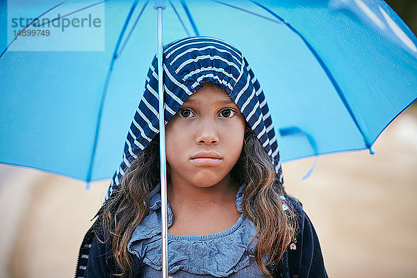 Porträt eines Mädchens mit Regenschirm  das während der Regenzeit einen Regenmantel trägt