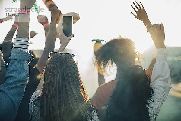 Frau hält Smartphone in der Hand  während sie mit Freunden beim Musikfestival genießt