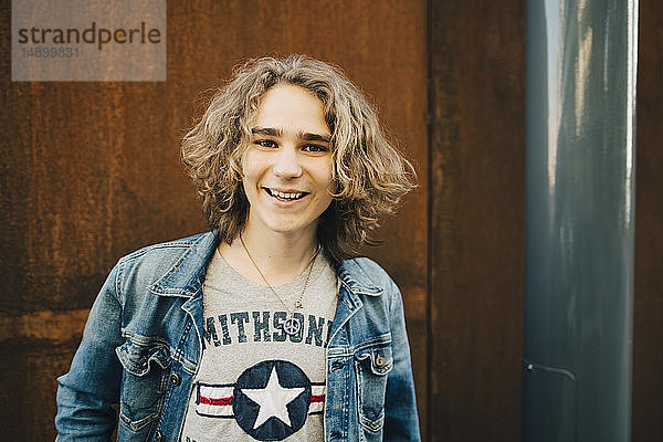 Porträt eines lächelnden jungen Mannes in Jeansjacke in der Stadt