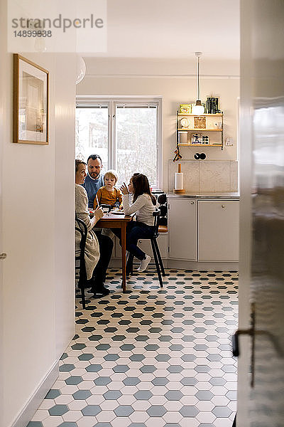 Familie beim gemeinsamen Essen in der Küche durch den Flur zu Hause gesehen