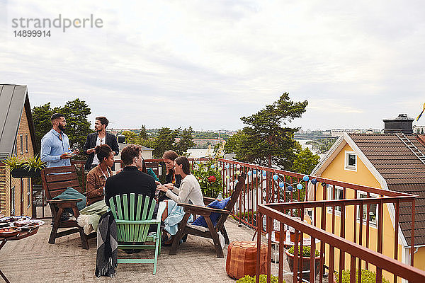 Freunde unterhalten sich  während sie ihre Freizeit auf der Terrasse gegen den Himmel verbringen