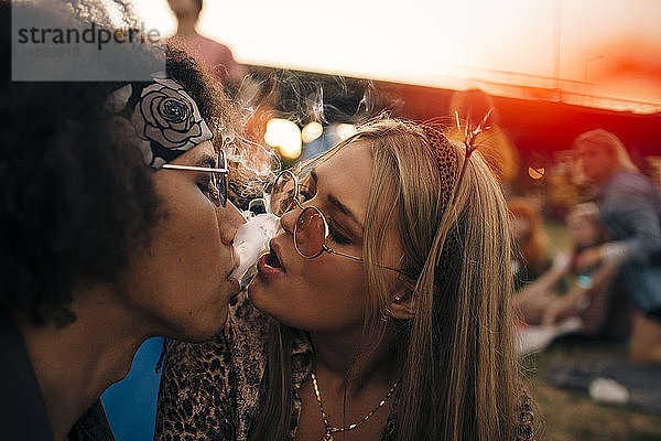 Nahaufnahme eines rauchenden Paares bei einer Musikveranstaltung
