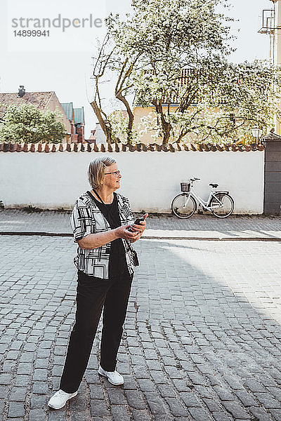 Ältere weibliche Touristin in voller Länge auf der Straße in der Stadt stehend