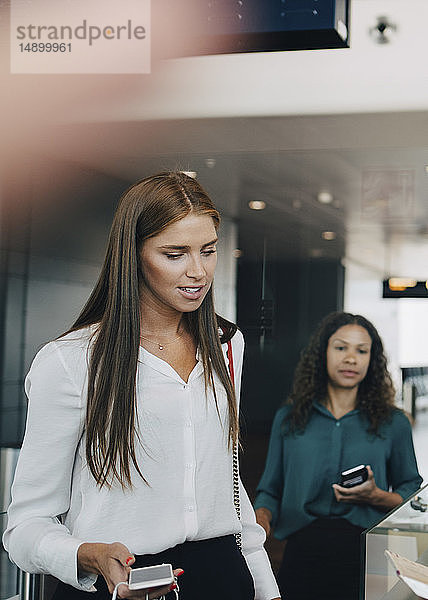 Junge Geschäftsfrau durchläuft Check-in-Prozess am Flughafen