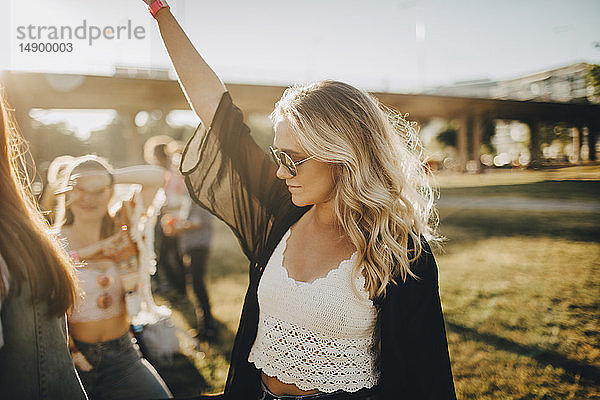 Junge Frau tanzt beim Musikfestival an einem sonnigen Tag