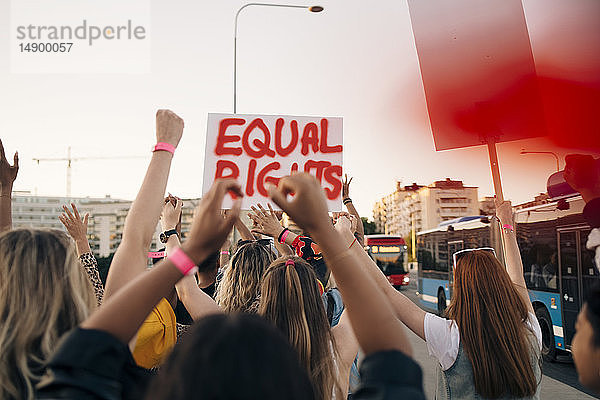 Rückansicht von Frauen mit Transparenten  die für Gleichberechtigung in der Stadt marschieren