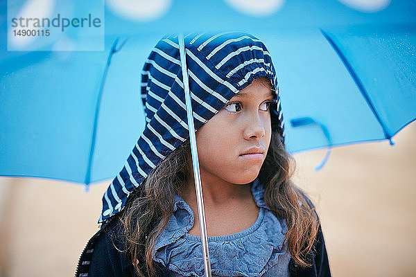 Mädchen mit Regenschirm schaut während der Regenzeit weg