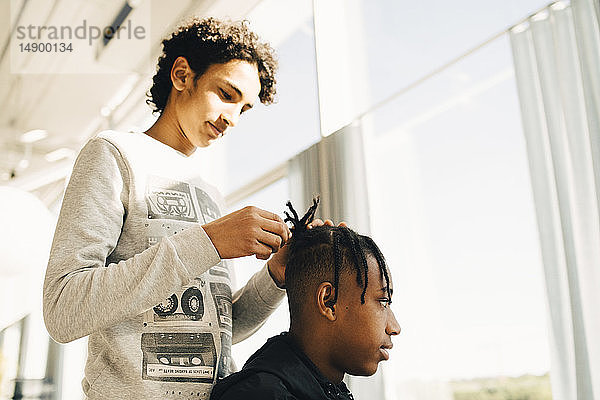 Teenager Junge frisiert die Haare eines Freundes  während er im Restaurant steht