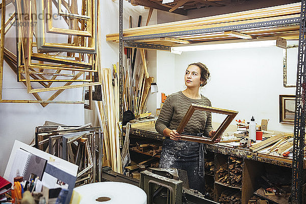 Selbstbewusste junge Handwerkerin hält den Rahmen beim Workshop