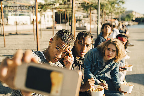Männliche Freunde  die sich während des Essens egoistisch verhalten  gehen in der Stadt auf der Straße essen