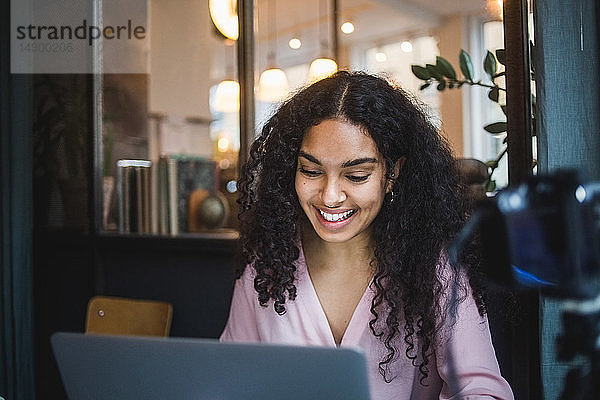 Lächelnde junge Geschäftsfrau benutzt Laptop im Kreativbüro