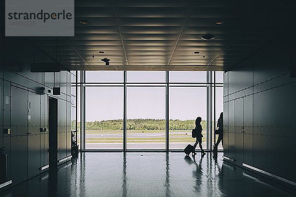 Ganzflächige Silhouette von Geschäftskolleginnen  die im Korridor am Flughafen gehen