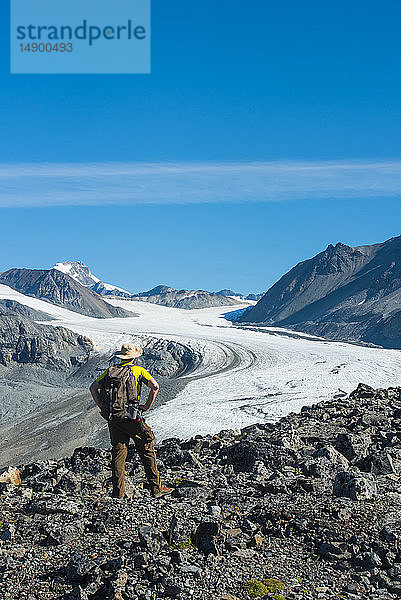 Ein Mann spaziert an einem sonnigen Sommernachmittag im Gulkana Glacier Valley in der Eastern Alaska Range in Süd-Zentral-Alaska; Alaska  Vereinigte Staaten von Amerika
