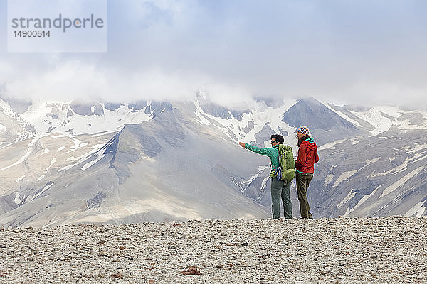 Zwei Frauen wandern und betrachten die Landschaft des Valley of Ten Thousand Smokes mit dem Mount Katmai im Hintergrund  Katmai National Park and Preserve  Südwest-Alaska; Alaska  Vereinigte Staaten von Amerika