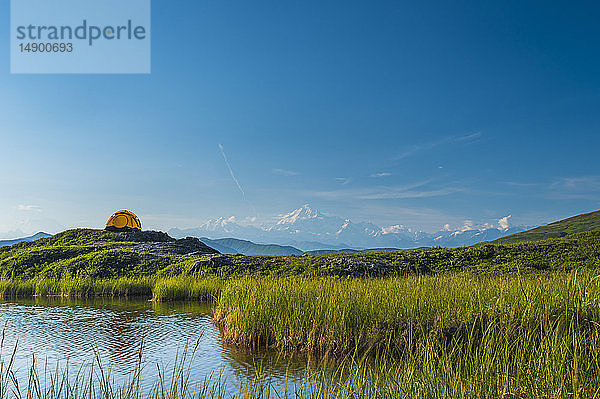 Zelt auf einem kleinen Hügel in der Tundra in der Nähe von Wasser mit der Alaska Range im Hintergrund  Denali State Park  Inner-Alaska; Alaska  Vereinigte Staaten von Amerika