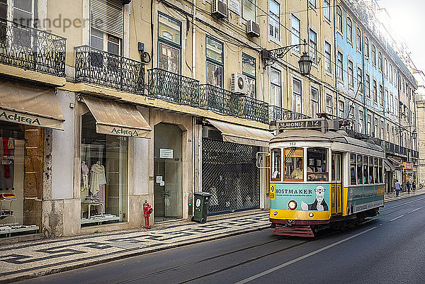 Straßenbahn auf einer Straße  die an Ladengeschäften vorbeiführt; Lissabon  Portugal
