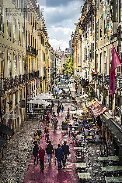 Fußgänger  die eine schmale Straße zwischen Gebäuden mit Restaurantterrassen und Ladenfronten in Bairro Alto  Lissabon  hinuntergehen; Lissabon  Portugal