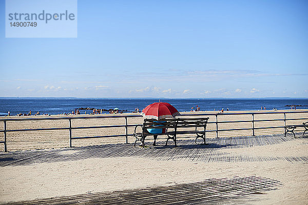 Frau mit Regenschirm auf der Promenade von Coney Island mit Blick auf den Atlantischen Ozean; New York City  New York  Vereinigte Staaten von Amerika