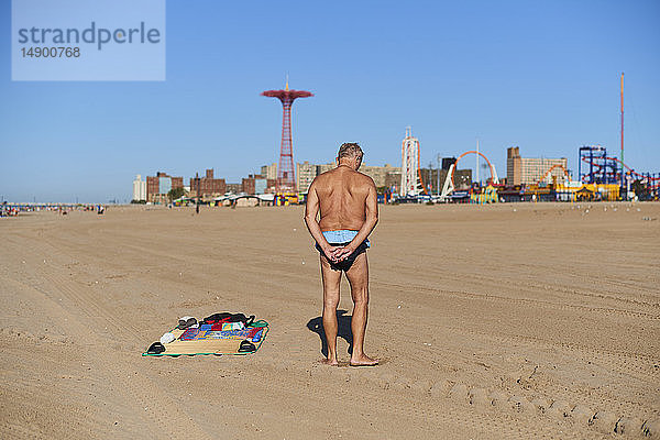 Mann im Badeanzug dehnt sich am Strand von Coney Island; New York City  New York  Vereinigte Staaten von Amerika
