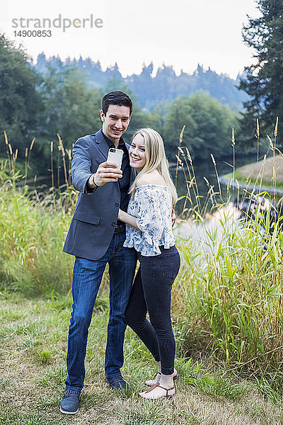 Ein junges Paar nimmt ein Selbstporträt mit einem Smartphone auf; Bothell  Washington  Vereinigte Staaten von Amerika