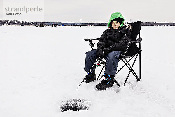 Junge wartet geduldig auf einen Biss beim Eisfischen am Wabamun Lake; Wabamun  Alberta  Kanada