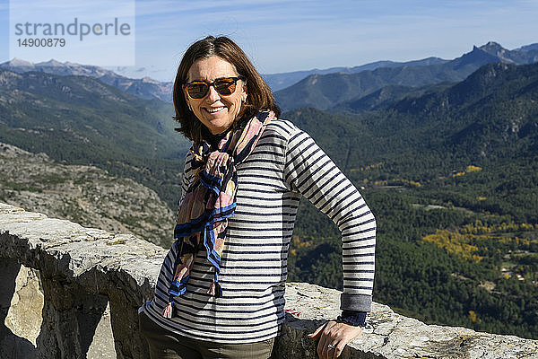 Eine reife Frau steht lächelnd für die Kamera mit der Sierra de Cazorla im Hintergrund; Cazorla  Provinz Jaen  Spanien
